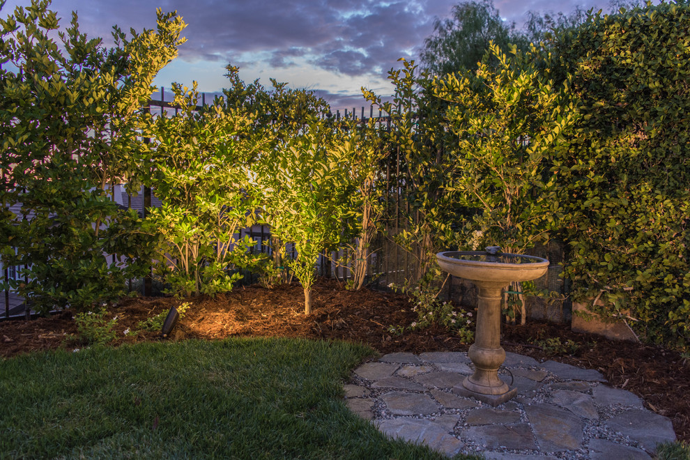 На фото: большой тенистый садовый фонтан на заднем дворе в средиземноморском стиле с покрытием из каменной брусчатки