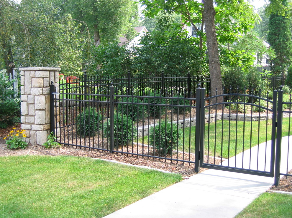 Idée de décoration pour un grand jardin arrière tradition avec une clôture en métal.