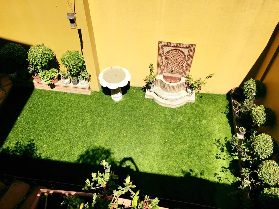 Cette image montre un petit jardin sur cour méditerranéen avec un point d'eau et une exposition partiellement ombragée.