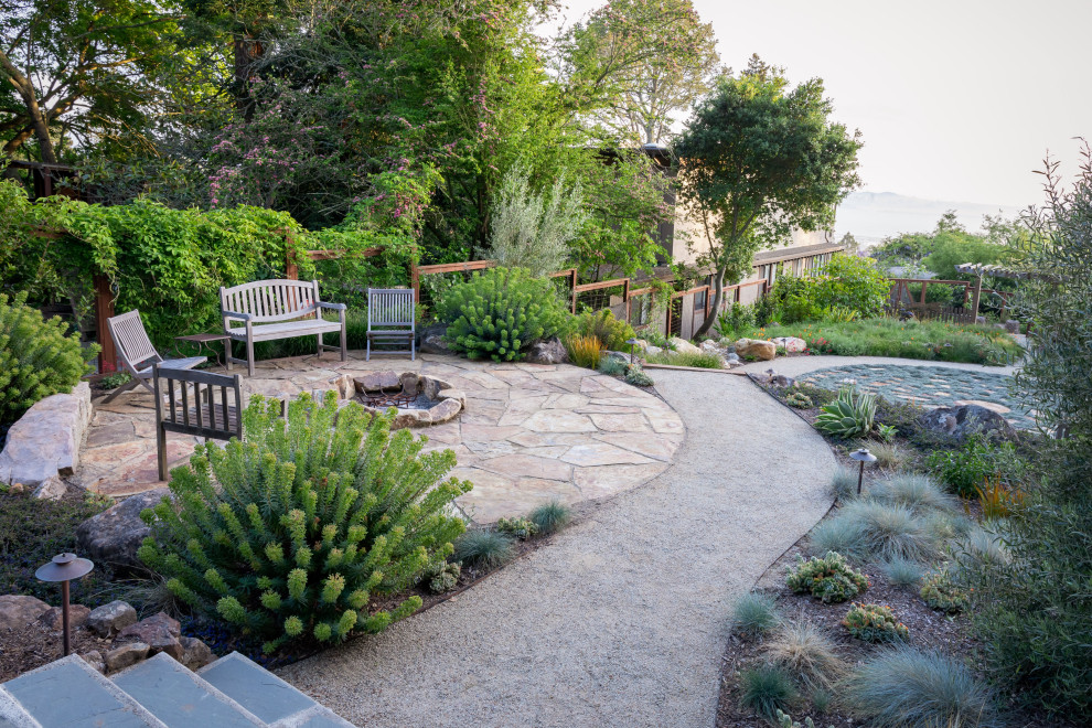 Imagen de jardín de secano actual grande en primavera en patio trasero con brasero, exposición total al sol y adoquines de piedra natural