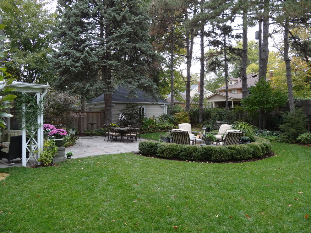 Идея дизайна: осенний регулярный сад среднего размера на заднем дворе в стиле неоклассика (современная классика) с полуденной тенью, покрытием из каменной брусчатки и местом для костра