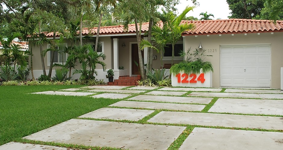 This is an example of a mid-sized rustic partial sun front yard concrete paver driveway in Miami.