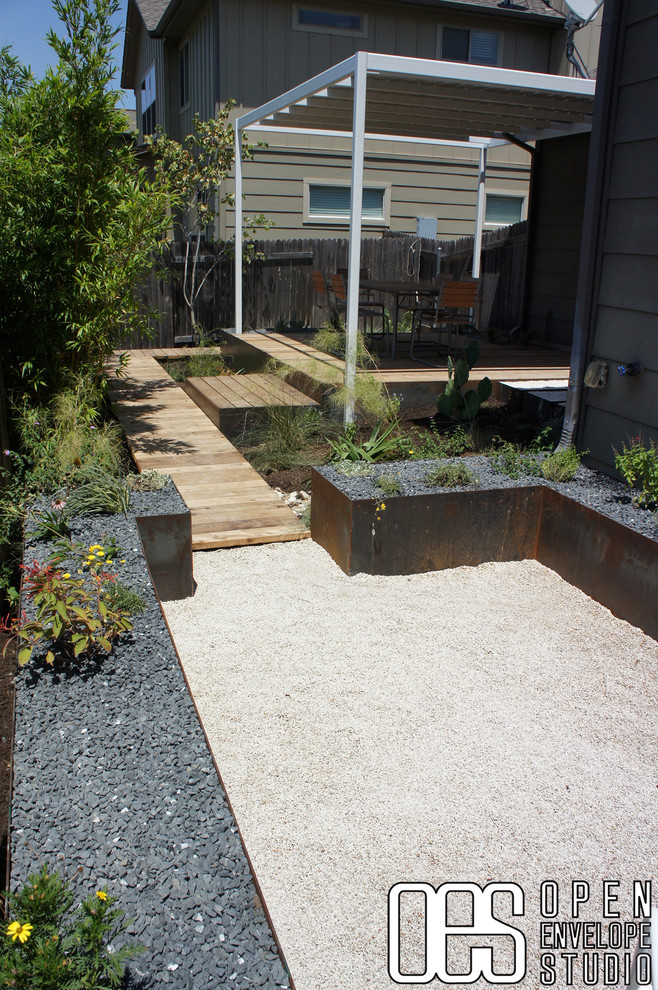 На фото: засухоустойчивый сад среднего размера на заднем дворе в стиле модернизм с полуденной тенью, покрытием из гравия и подпорной стенкой с