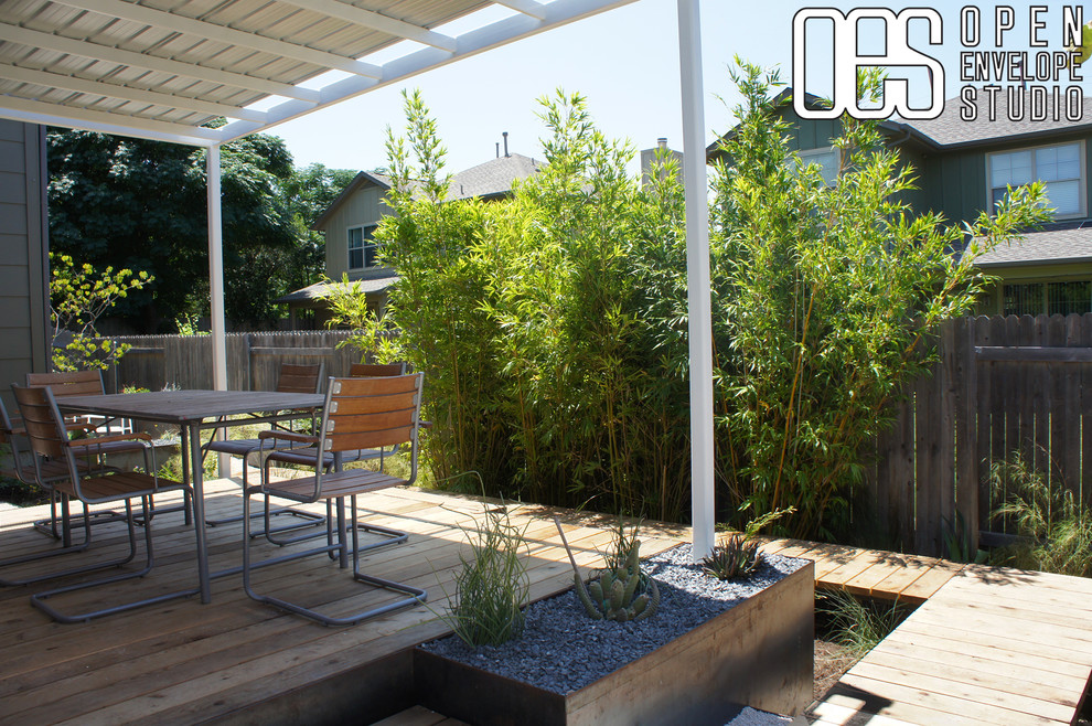 This is an example of a mid-sized modern partial sun backyard retaining wall landscape in Austin with decking.