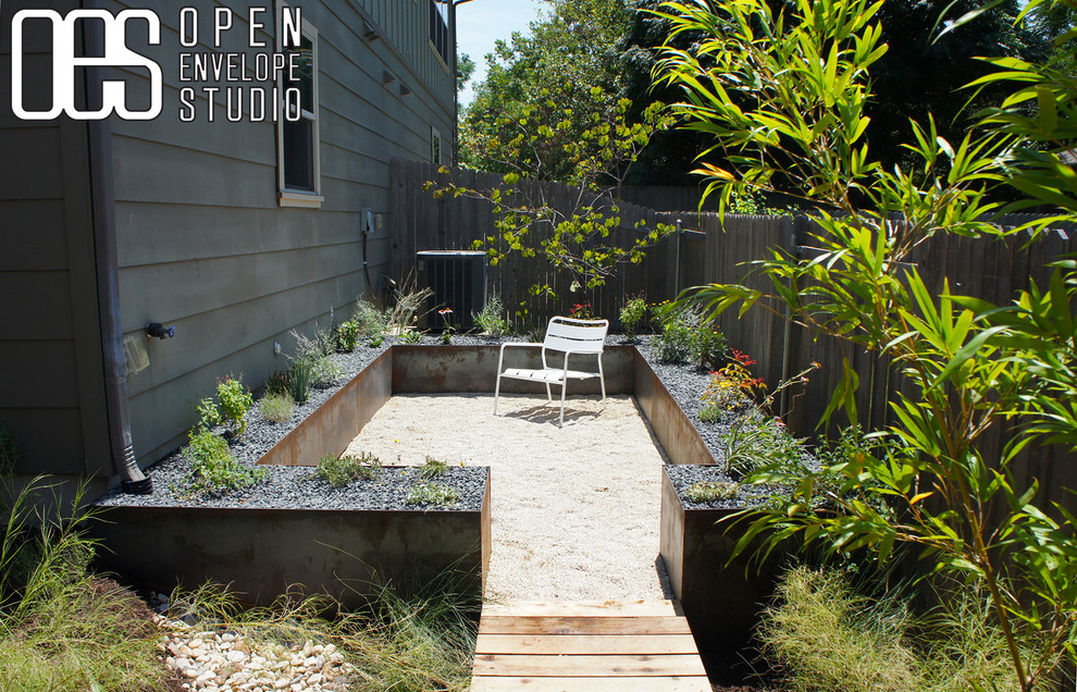 Пример оригинального дизайна: засухоустойчивый сад среднего размера на заднем дворе в стиле модернизм с полуденной тенью, покрытием из гравия и подпорной стенкой