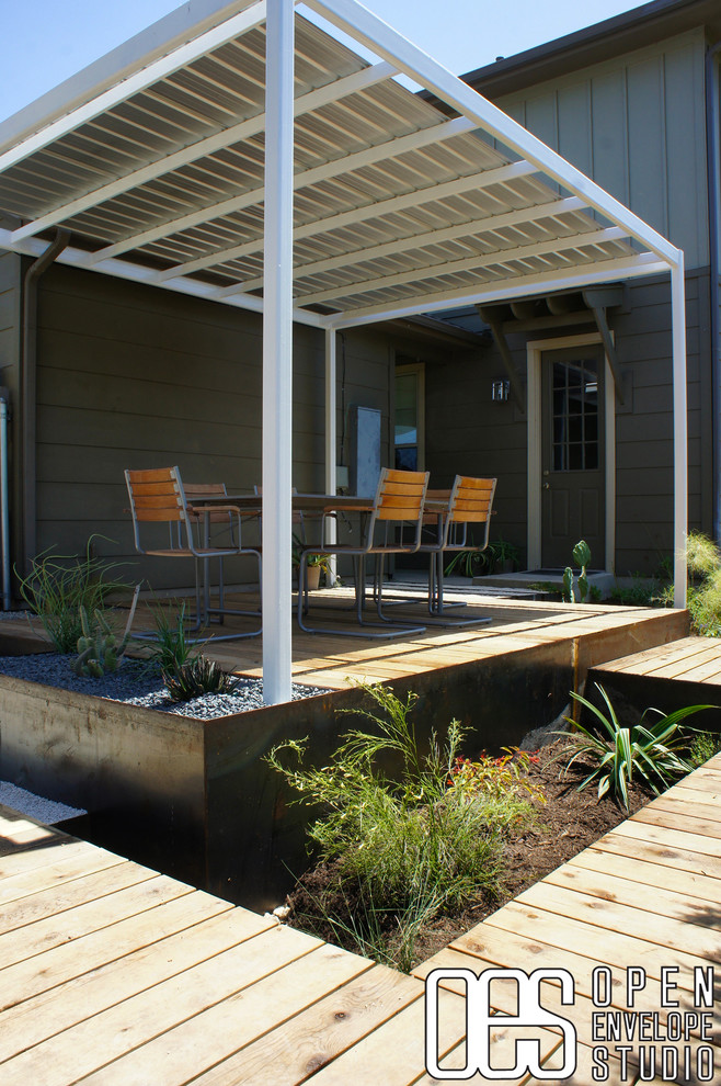 Photo of a medium sized modern back partial sun garden in Austin with a retaining wall and decking.