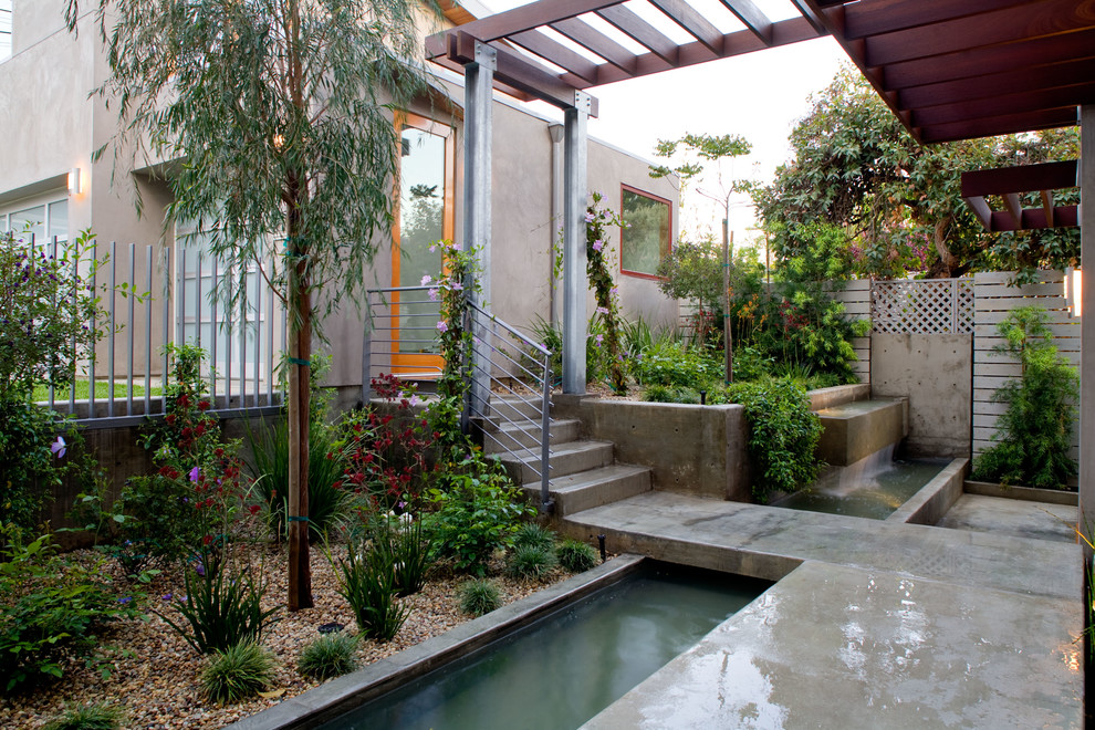 Ejemplo de jardín moderno de tamaño medio en patio trasero con estanque, exposición reducida al sol y adoquines de hormigón