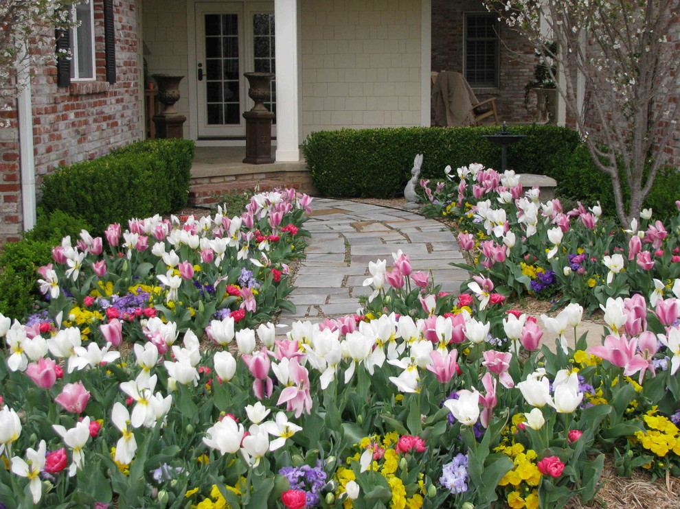 Klassisk inredning av en trädgård framför huset och blomsterrabatt på våren