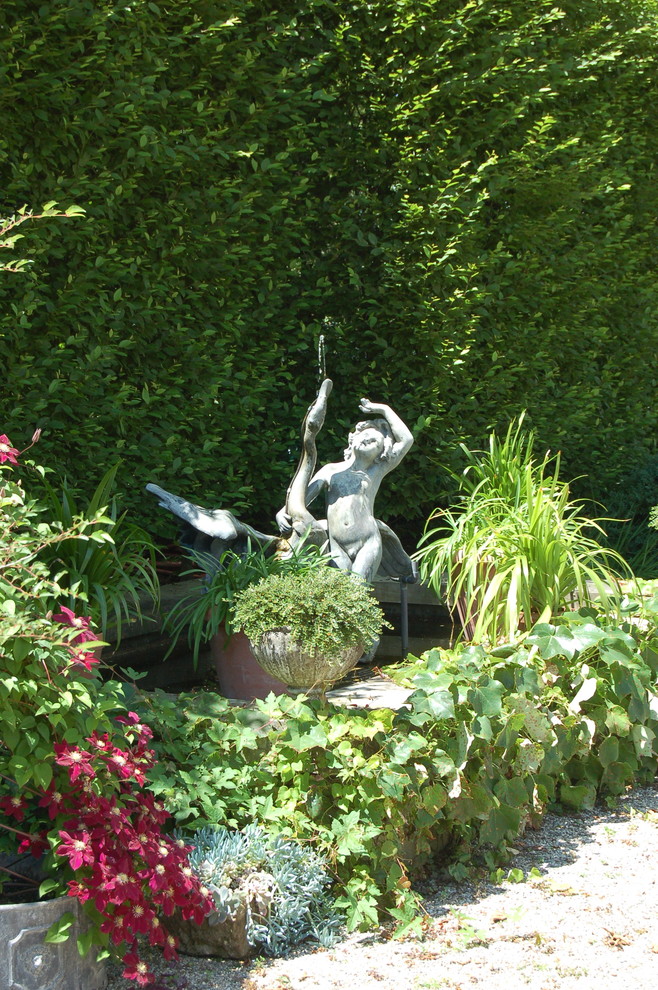 Inredning av en klassisk stor trädgård i delvis sol på sommaren, med en fontän och grus