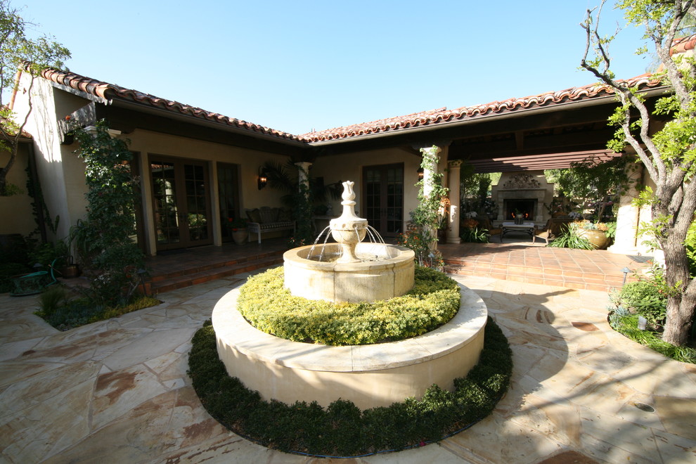 This is an example of a large mediterranean partial sun backyard stone water fountain landscape in New York.