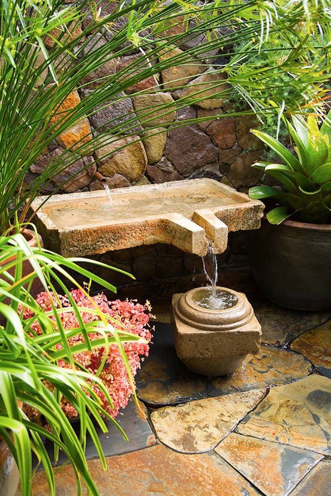 Photo of a small bohemian back formal partial sun garden for summer in San Francisco with a water feature and natural stone paving.