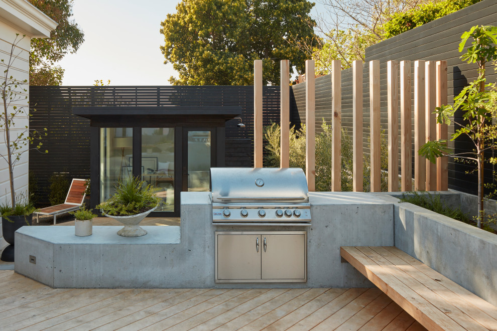 Cette photo montre un grand xéropaysage arrière moderne avec un foyer extérieur, une exposition ensoleillée et une terrasse en bois.