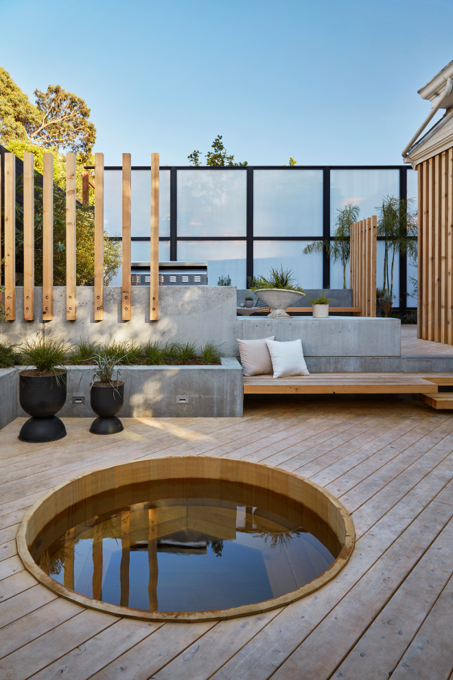 Aménagement d'un grand xéropaysage arrière moderne avec un foyer extérieur, une exposition ensoleillée et une terrasse en bois.