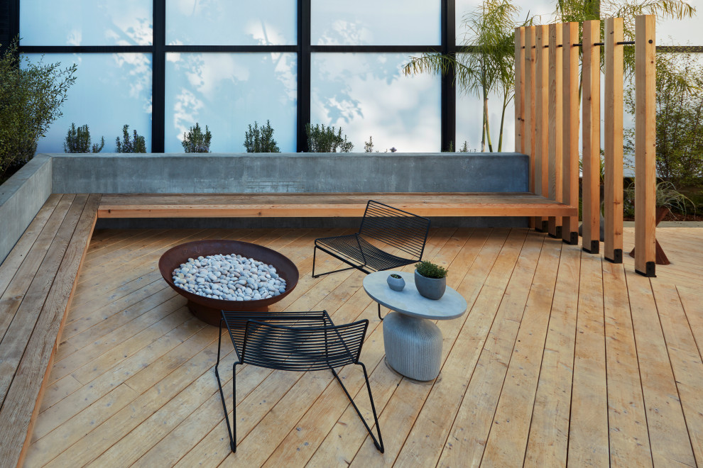 Idée de décoration pour un grand xéropaysage arrière minimaliste avec un foyer extérieur, une exposition ensoleillée et une terrasse en bois.