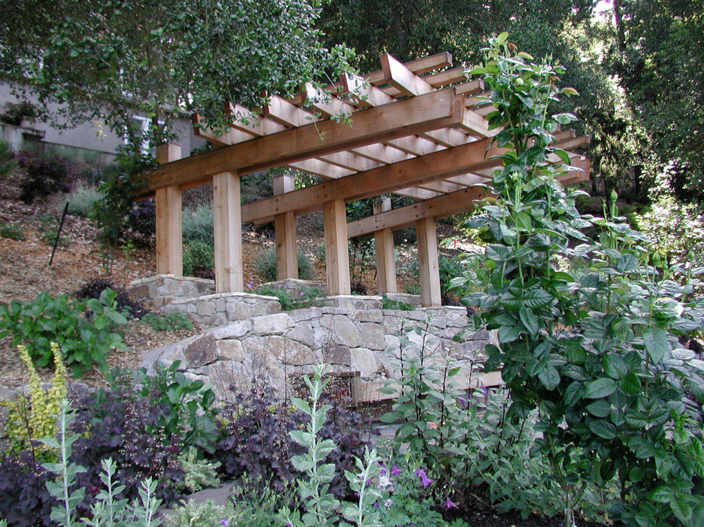 Foto di un piccolo giardino formale stile americano esposto a mezz'ombra dietro casa in estate con un muro di contenimento e pacciame