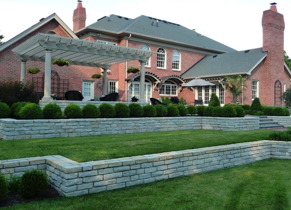 This is an example of a huge traditional shade backyard mulch retaining wall landscape in Cincinnati.
