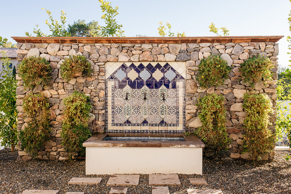 Immagine di un ampio giardino formale mediterraneo nel cortile laterale con fontane e pavimentazioni in pietra naturale