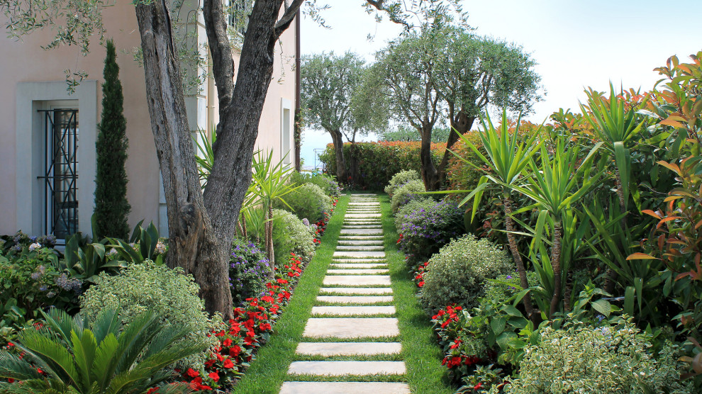 Réalisation d'un aménagement d'entrée ou allée de jardin avant méditerranéen avec une exposition partiellement ombragée et des pavés en pierre naturelle.