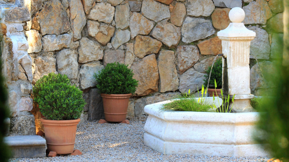Cette image montre un jardin méditerranéen avec du gravier et un point d'eau.