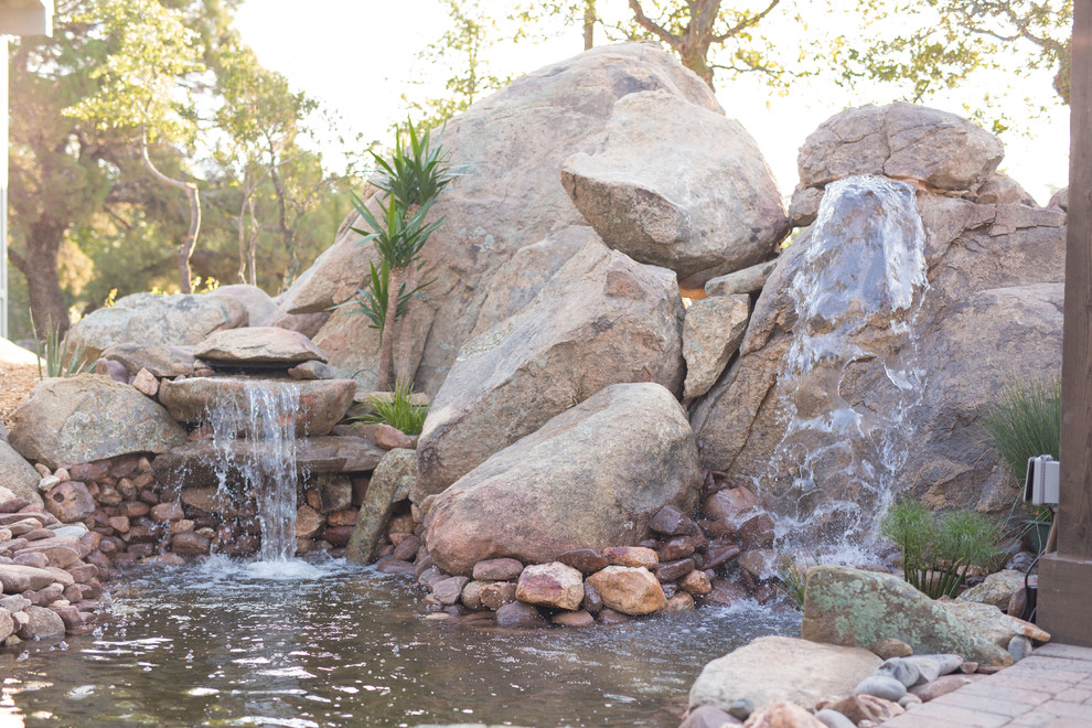 Réalisation d'un grand jardin arrière sud-ouest américain avec un bassin, une exposition partiellement ombragée et des pavés en pierre naturelle.