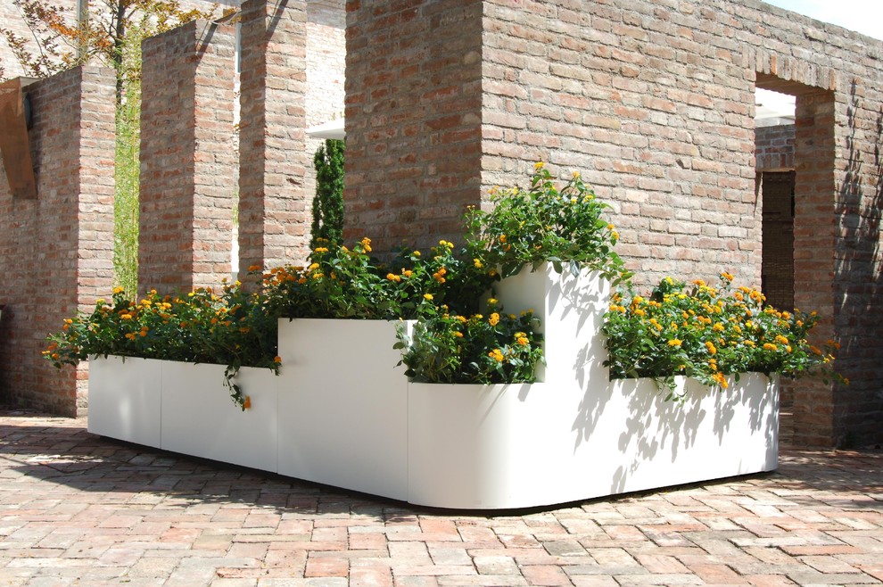 Ispirazione per un giardino design esposto in pieno sole in cortile in estate con un giardino in vaso e pavimentazioni in mattoni