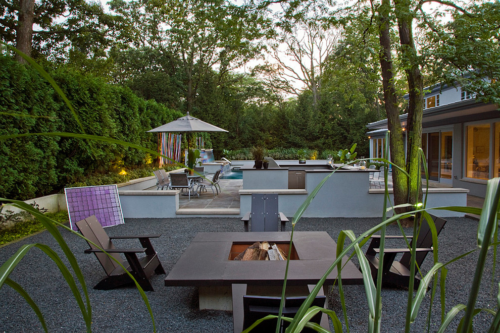 This is an example of a medium sized contemporary back full sun garden in Chicago with a fire feature and gravel.