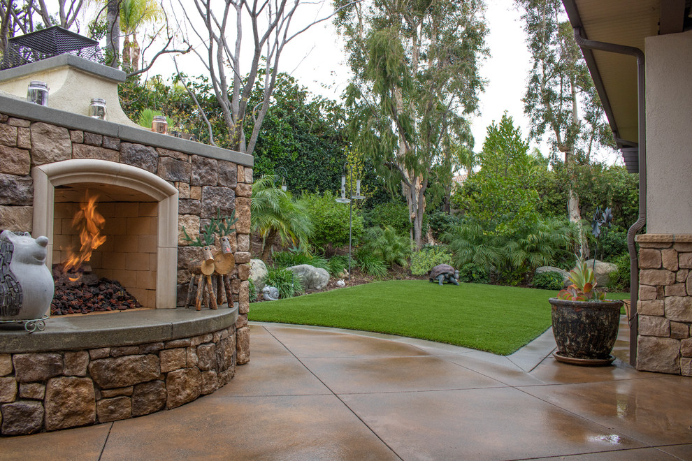 Immagine di un giardino xeriscape country esposto in pieno sole dietro casa con un caminetto e pavimentazioni in cemento