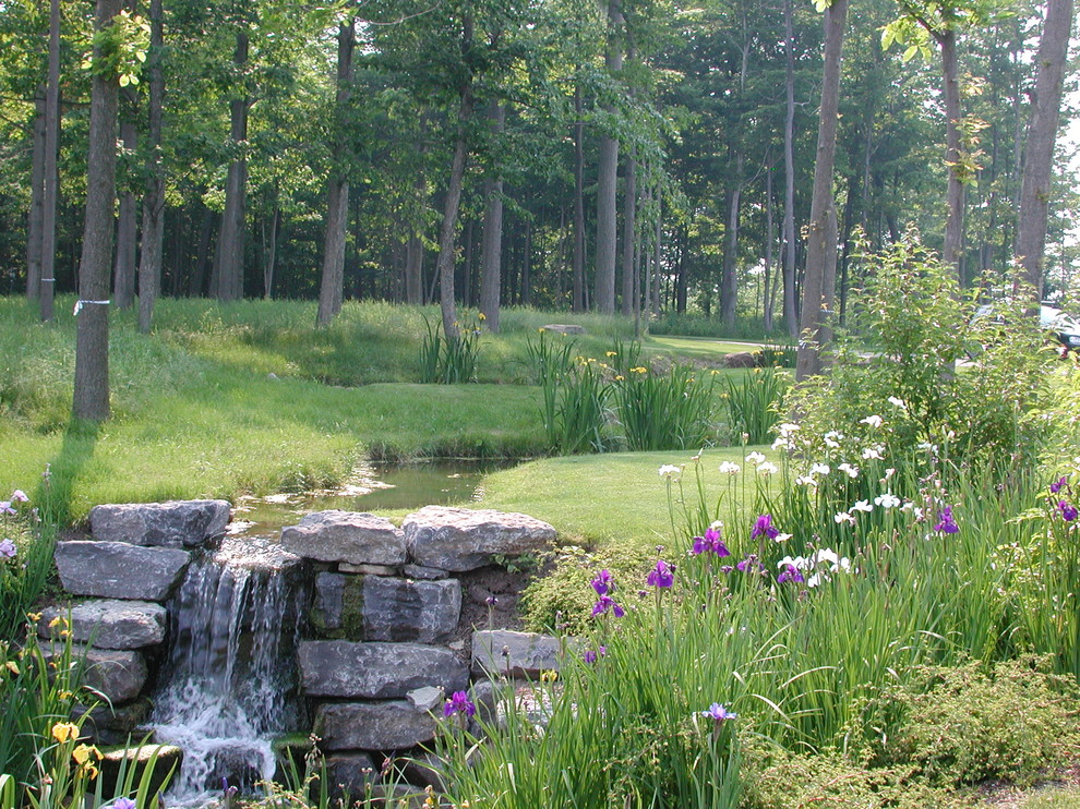 Immagine di un grande giardino country esposto in pieno sole dietro casa in primavera con fontane e pavimentazioni in pietra naturale