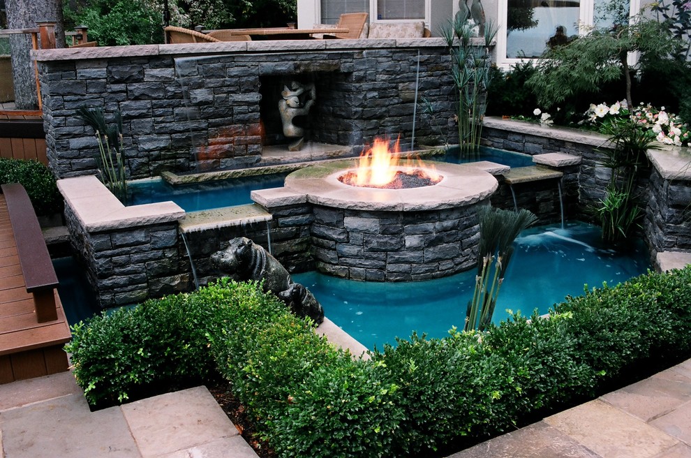 Imagen de jardín actual en patio trasero con fuente y adoquines de piedra natural