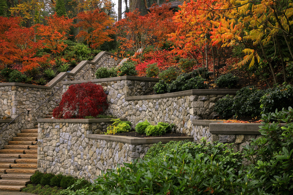 This is an example of a world-inspired sloped garden for autumn in Vancouver with natural stone paving.