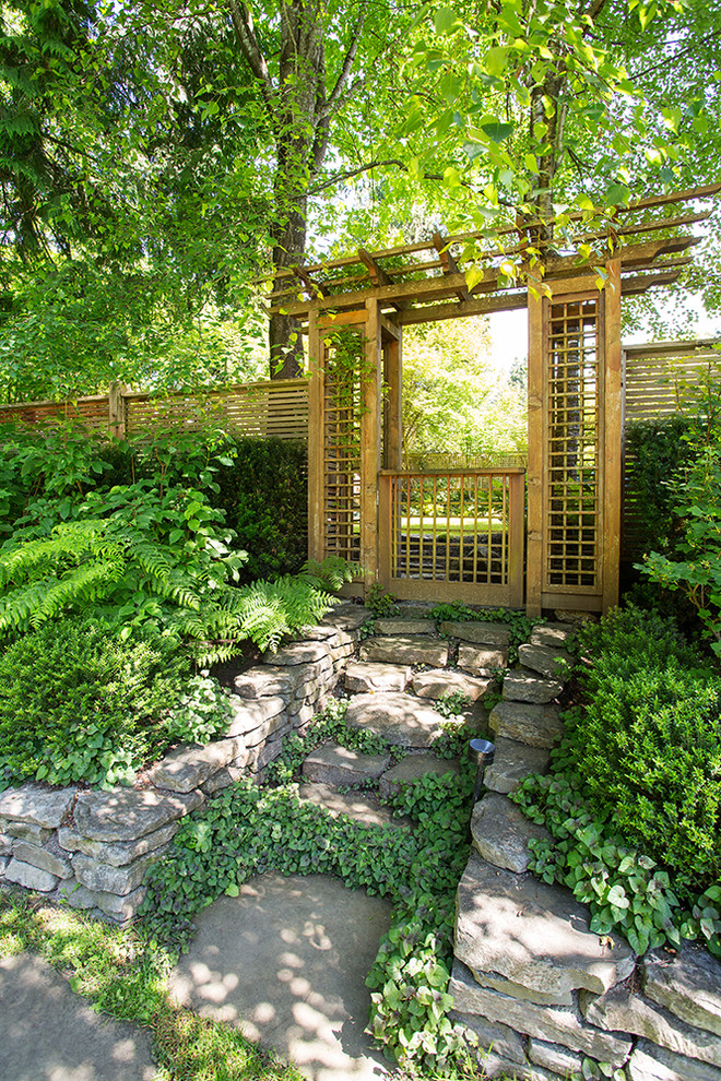 На фото: участок и сад на склоне в восточном стиле с покрытием из каменной брусчатки и забором с