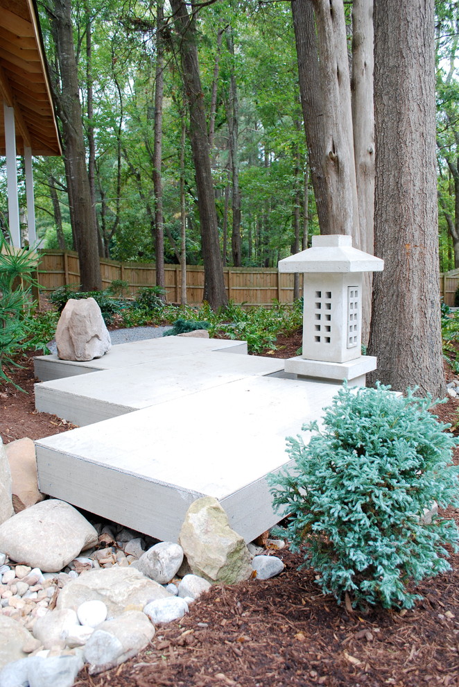 Exemple d'un jardin arrière asiatique avec des pavés en béton et pierres et graviers.