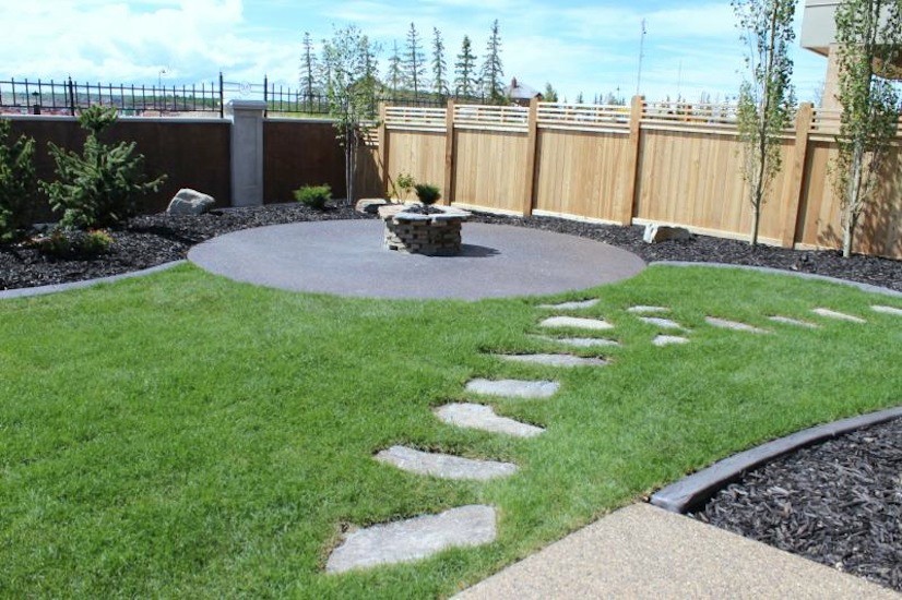 Medium sized back garden in Calgary with a fire feature and natural stone paving.