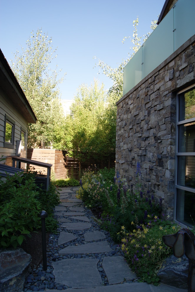 Diseño de jardín actual de tamaño medio en patio lateral con exposición parcial al sol y adoquines de piedra natural