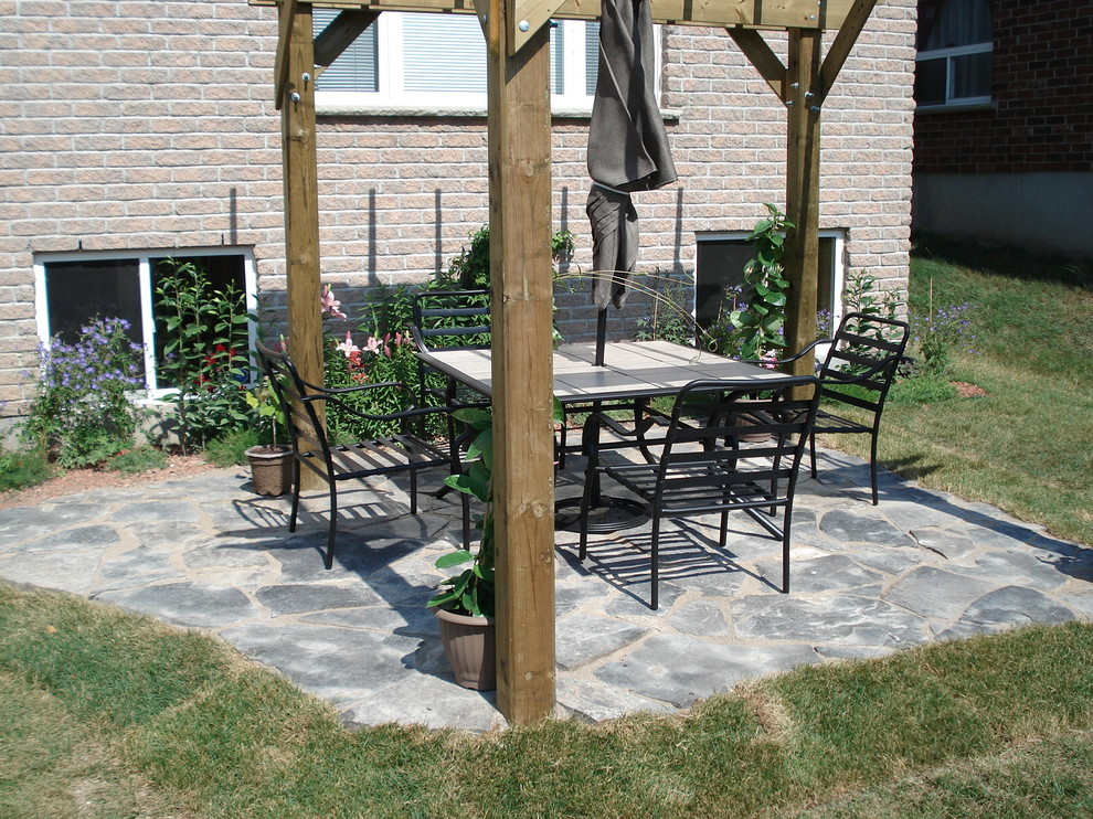Inspiration for a large contemporary back patio in Toronto with brick paving.