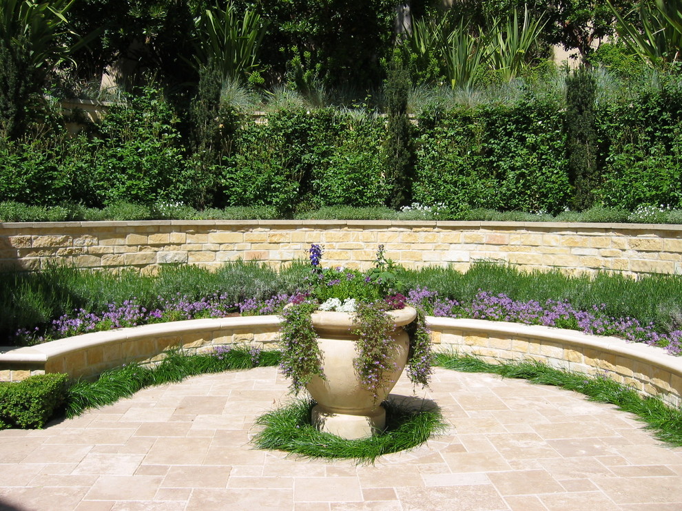 Réalisation d'un grand jardin sur cour méditerranéen avec un mur de soutènement, une exposition ensoleillée et des pavés en brique.