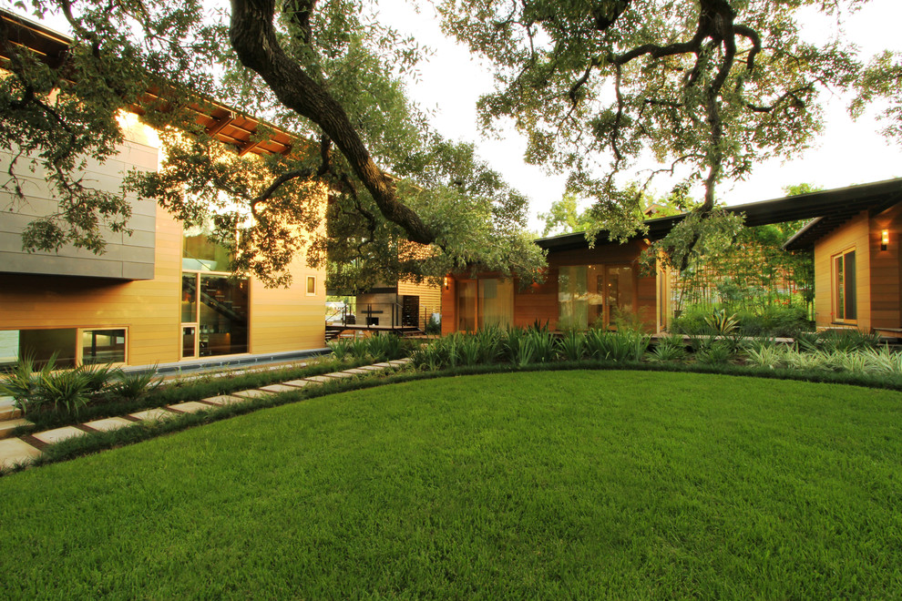 This is an example of a mid-sized contemporary full sun backyard mulch landscaping in Austin for summer.