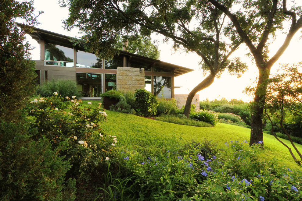Photo of a large modern partial sun hillside landscaping in Austin.