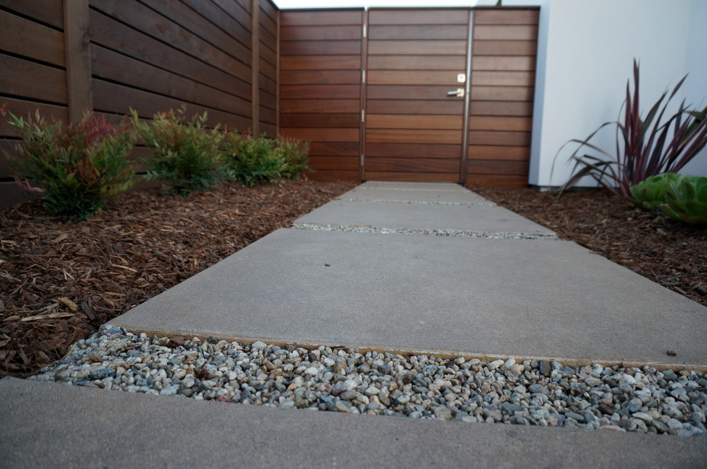 Idée de décoration pour un aménagement d'entrée ou allée de jardin avant minimaliste de taille moyenne avec une exposition ensoleillée et des pavés en béton.