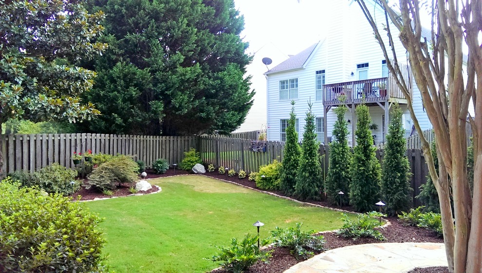Ejemplo de jardín tradicional en patio delantero con muro de contención y adoquines de piedra natural