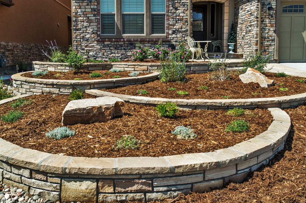 Large rustic front xeriscape partial sun garden for summer in Denver with a retaining wall and natural stone paving.