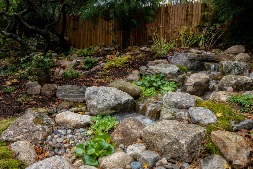 Geometrischer, Kleiner, Halbschattiger Asiatischer Gartenwasserfall im Herbst, hinter dem Haus in Boston