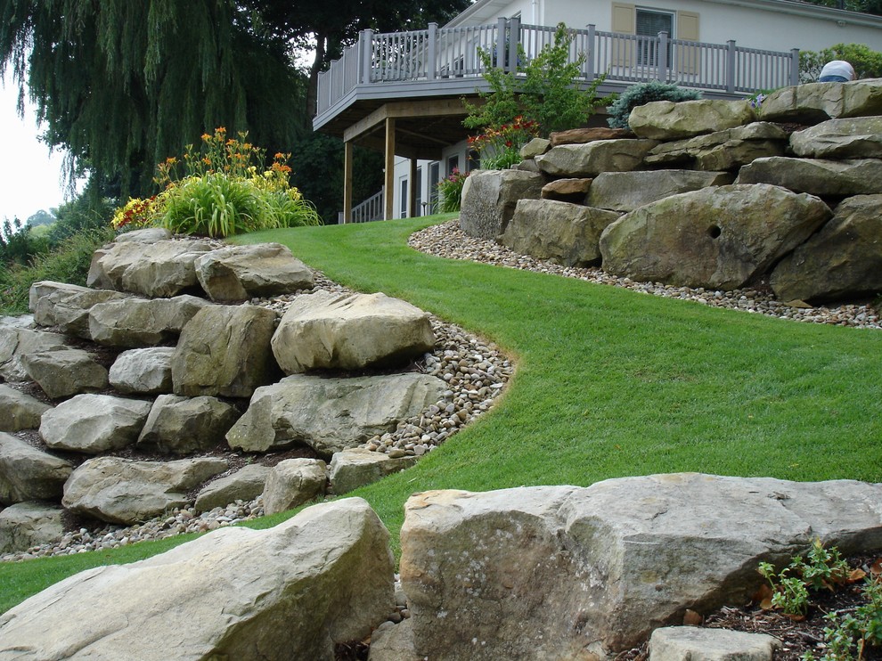 Photo of a large transitional full sun backyard stone retaining wall landscape in Cleveland for summer.