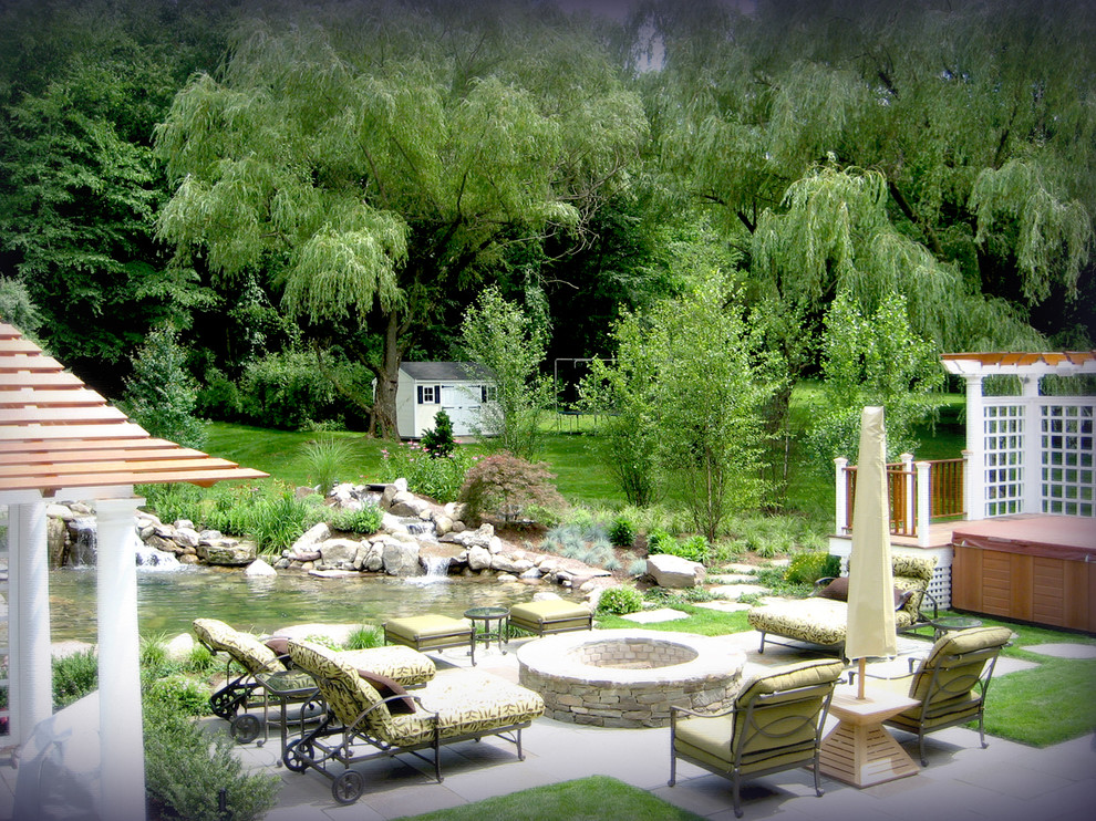 This is an example of a mid-sized traditional full sun backyard stone landscaping in New York for spring.