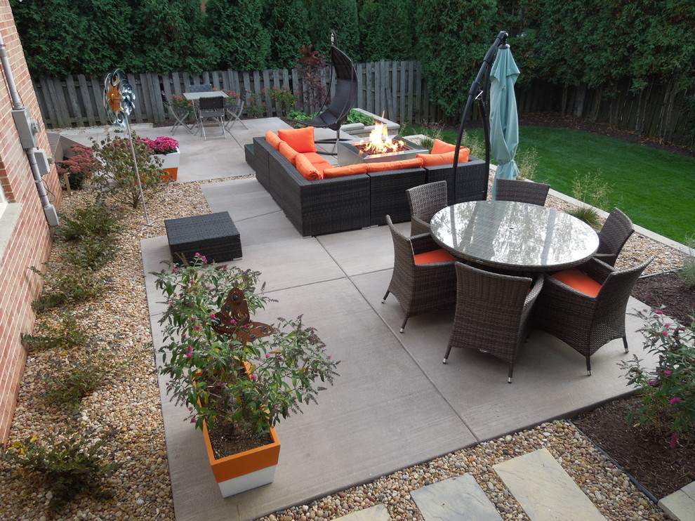 This is an example of a medium sized modern back patio in Milwaukee with a fire feature and concrete paving.