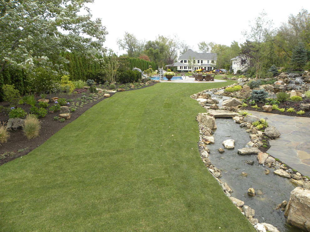 Photo of a huge traditional partial sun backyard stone water fountain landscape in Chicago for summer.