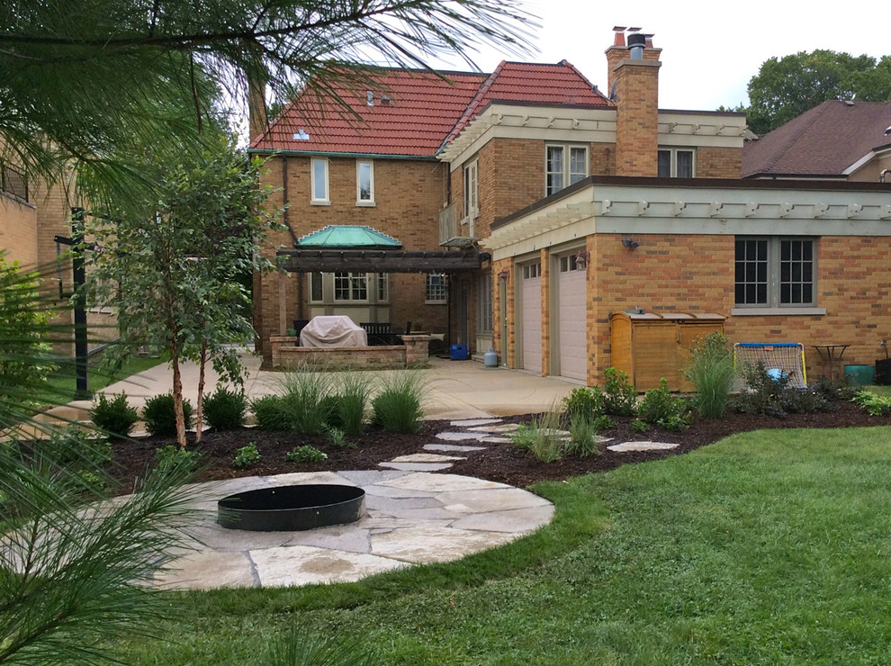 Medium sized traditional back full sun garden for autumn in Chicago with a fire feature and natural stone paving.