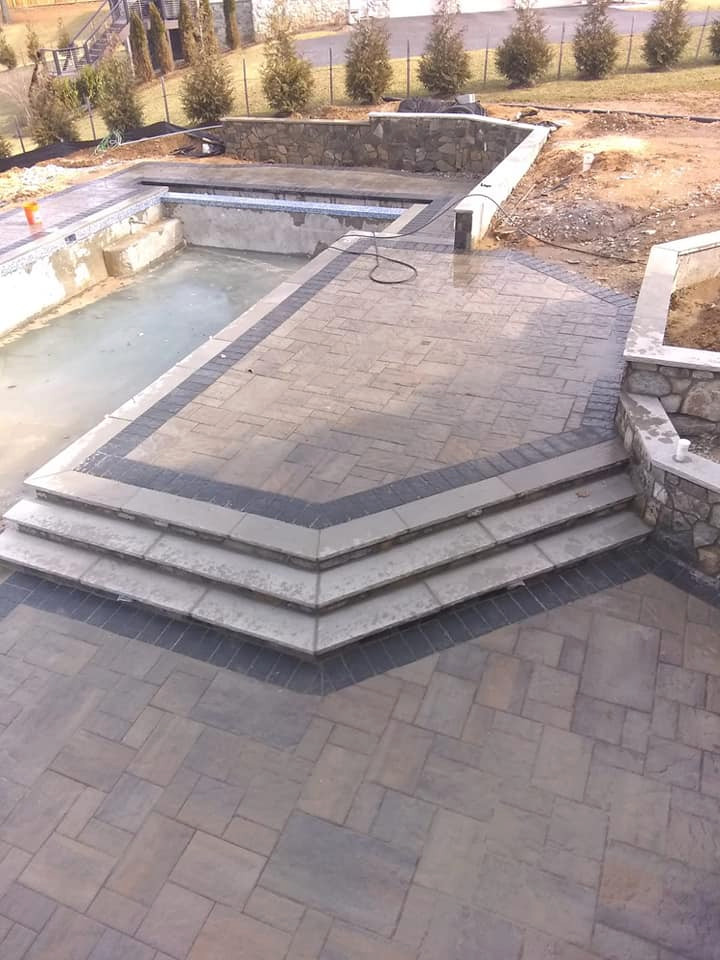 Photo of a large world-inspired back full sun garden for summer in DC Metro with a retaining wall and concrete paving.