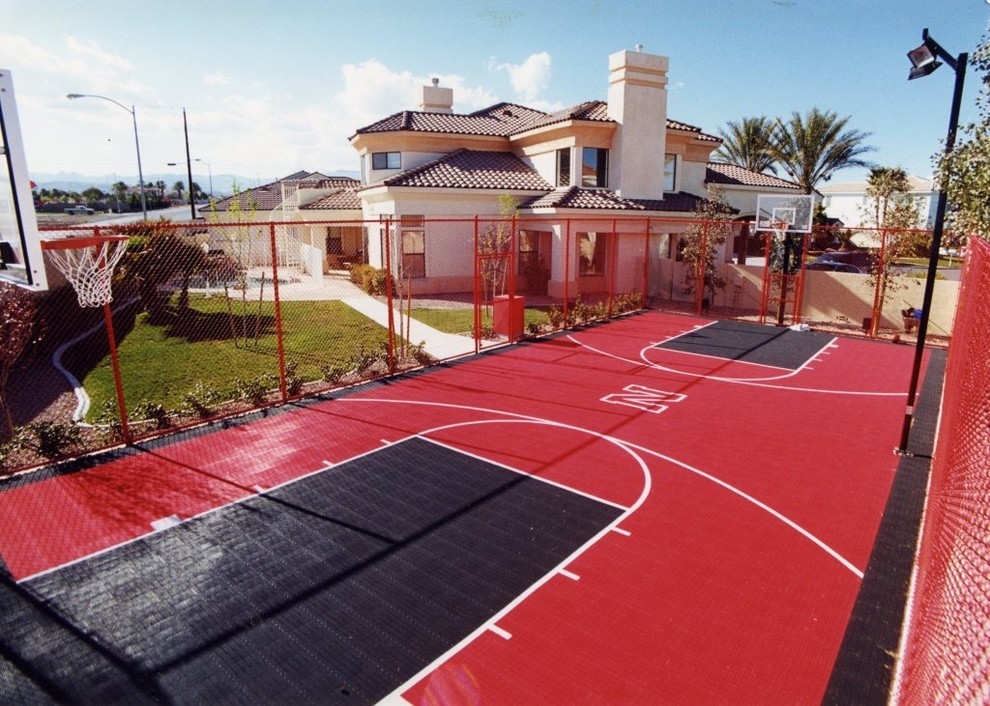 Foto di un grande campo sportivo esterno moderno esposto in pieno sole dietro casa con uno spazio giochi