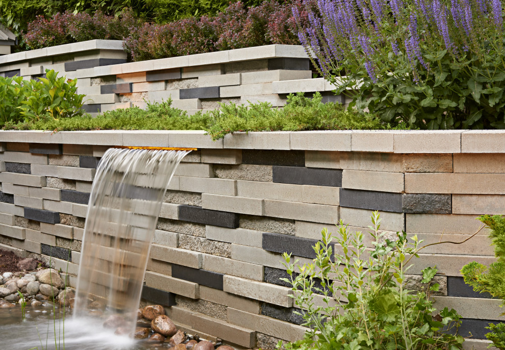 Design ideas for an eclectic backyard concrete paver retaining wall landscape in Toronto.